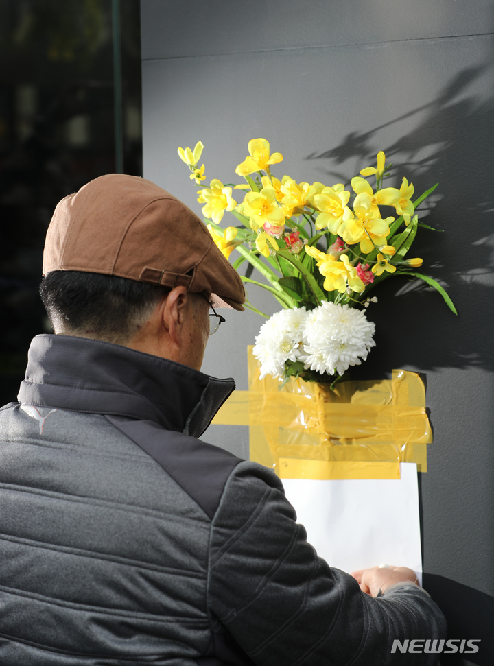 [서울=뉴시스] 김금보 기자 = 30일 오후 서울 용산구 이태원 할로윈 참사 현장 인근 건물 외벽에 한 시민이 근조화를 부착하고 애도하고 있다. 2022.10.25. kgb@newsis.com