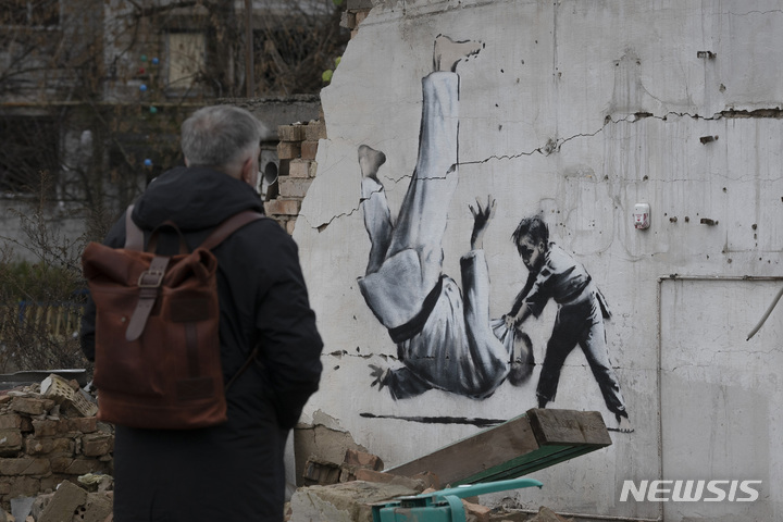 [보로디안카=AP/뉴시스]지난해 11월 13일(현지시간) 우크라이나 수도 키이우 인근 도시인 보로디안카에 얼굴 없는 그라피티 아티스트 뱅크시가 그린것으로 추정되는 벽화가 보이고 있다. 2023.02.25.