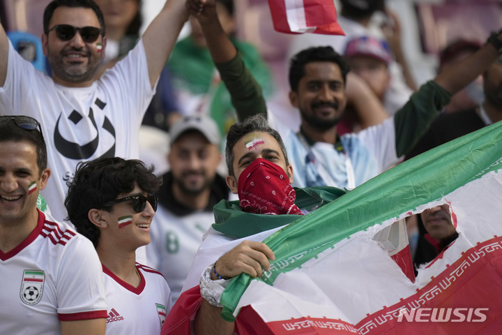 [도하=AP/뉴시스] 이란 축구팬들이 21일(한국시간) 카타르 도하의 칼리파 국제경기장에서 열린 잉글랜드와 2022 FIFA 카타르 월드컵 B조 첫 경기 시작 직전 국장이 새겨진 가운데 부분이 오려진 이란 국기를 들어보이고 있다. 2022.11.21.