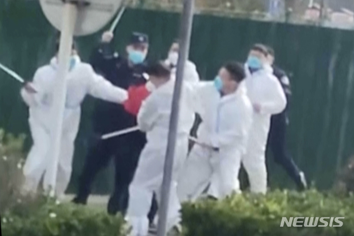 [정저우=AP/뉴시스]  23일 중국 허난성 정저우의 폭스콘 공장에서 시위 노동자와 방호복을 입은 보안요원들이 몸싸움을 벌이고 있다.