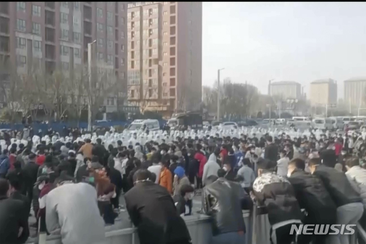 [정저우=AP/뉴시스] 23일 중국 허난성 정저우 폭스콘 공장에서 수백명의 노동자들이 시위를 벌인 가운데 방호복을 입은 보안요원들과 대치하고 있다. 2022.11.24
