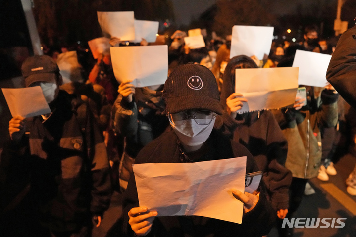 [베이징=AP/뉴시스] 지난 27일 베이징에서 열린 코로나19 봉쇄조치 항의 시위에서 시민들이 아무것도 쓰여있지 않은 흰색 종이를 들고 있다. 