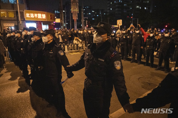 [베이징=AP/뉴시스] 27일 베이징에서 중국 경찰이 행진하는 시위대를 막기 위해 줄을 서 있다. 고강도 방역 규제로 바이러스 전파를 막는 '제로 코로나' 조치에 분노한 시위대는 시진핑 중국 국가 주석의 퇴진을 요구했고 이는 최소 8개 도시에서 집권 공산당에 직접적으로 도전한 전례 없는 시위였다. 2022.11.28.