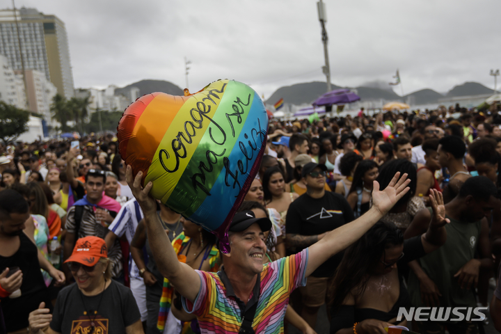 [리우데자네이루=AP/뉴시스] 27일(현지시간) 브라질 리우데자네이루 코파카바나 해변에서 제27회 게이 프라이드 퍼레이드(Gay Pride Parade)가 열린 가운데 한 남성이 포르투갈어로 "행복할 용기를"라고 적힌 하트 풍선을 들고 있다. 2022.11.28.