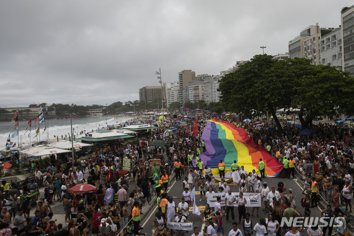 [리우데자네이루=AP/뉴시스] 27일(현지시간) 브라질 리우데자네이루 코파카바나 해변에서 제27회 게이 프라이드 퍼레이드(Gay Pride Parade)가 열려 참가자들이 대형 무지개 깃발을 들고 행진하고 있다. 2022.11.28.