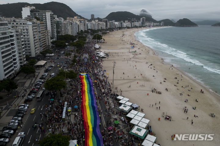 [리우데자네이루=AP/뉴시스] 27일(현지시간) 브라질 리우데자네이루 코파카바나 해변에서 제27회 게이 프라이드 퍼레이드(Gay Pride Parade)가 열려 한 여성이 대형 무지개 깃발 위에 앉아 사진 포즈를 취하고 있다. 2022.11.28.