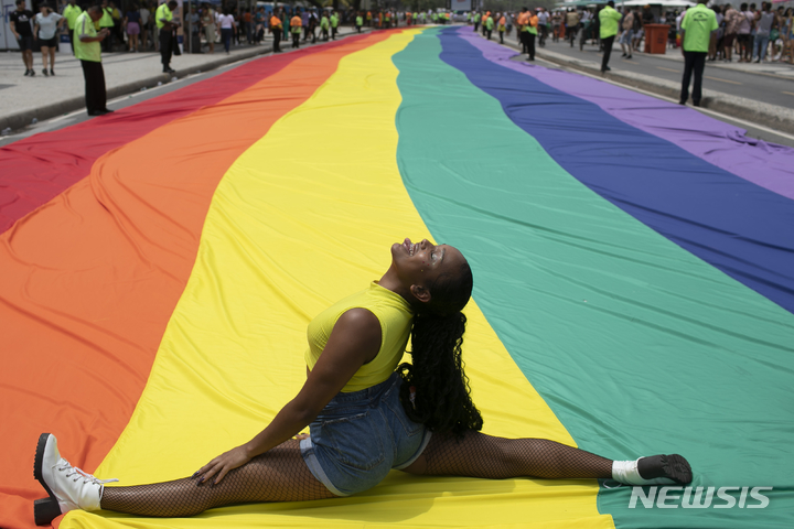 [리우데자네이루=AP/뉴시스] 27일(현지시간) 브라질 리우데자네이루 코파카바나 해변에서 제27회 게이 프라이드 퍼레이드(Gay Pride Parade)가 열려 한 여성이 대형 무지개 깃발 위에 앉아 사진 포즈를 취하고 있다. 2022.11.28.