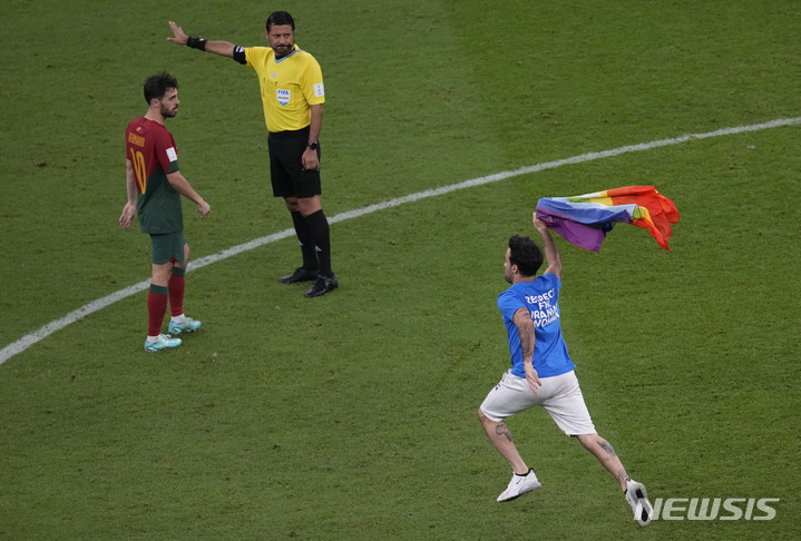 [루사일=AP/뉴시스] 28일(현지시간) 카타르 루사일 스타디움에서 열린 2022 카타르 월드컵 조별리그 H조 2차전 포르투갈과 우루과이의 경기 중 '이란 여성을 존중하라'라고 쓰인 셔츠를 입은 한 남성이 경기장에 난입해 무지개 깃발을 흔들고 있다. 2022.11.29.
