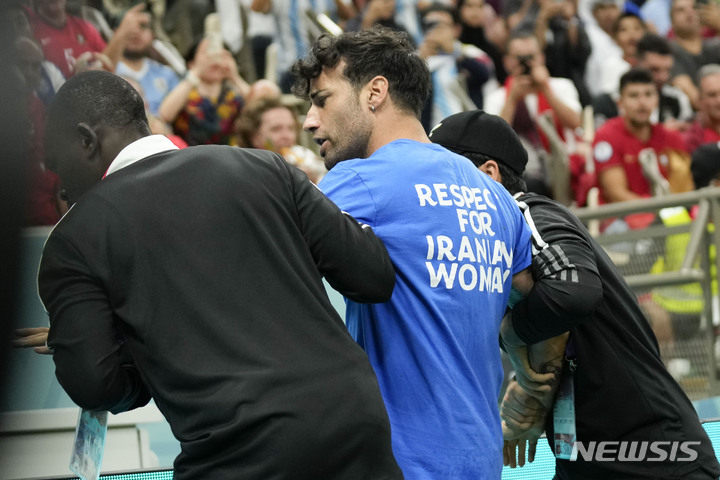 [루사일=AP/뉴시스] 28일(현지시간) 카타르 루사일 스타디움에서 열린 2022 카타르 월드컵 조별리그 H조 2차전 포르투갈과 우루과이의 경기 중 '이란 여성을 존중하라'라고 쓰인 셔츠를 입은 한 남성이 경기장에 난입해 관계자들에게 끌려 나가고 있다. 2022.11.29.