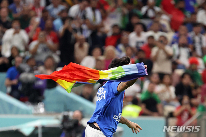[루사일(카타르)=뉴시스] 백동현 기자 = 28일(현지시간) 카타르 루사일 스타디움에서 열린 2022 카타르 월드컵 조별리그 H조 2차전 포르투갈과 우루과이의 경기, 한 남성이 무지개 색깔의 깃발을 흔들며 경기장에 난입하고 있다. 이 남성이 입은 셔츠 뒤에는 'RESPECT FOR IRANIAN WOMAN'라고 적혀있다. 2022.11.29. livertrent@newsis.com