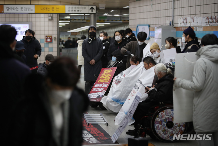 [서울=뉴시스] 김진아 기자 = 30일 오전 서울 용산구 삼각지역 4호선에서 전국장애인차별철폐연대가 장애인 권리 예산 확보를 위한 지하철 선전전을 하는 앞으로 시민들이 지나가고 있다. 이날 서울 지하철을 운영하는 서울교통공사 노동조합이 파업에 들어가면서 출근길 혼란이 불가피했다. 2022.11.30. bluesoda@newsis.com