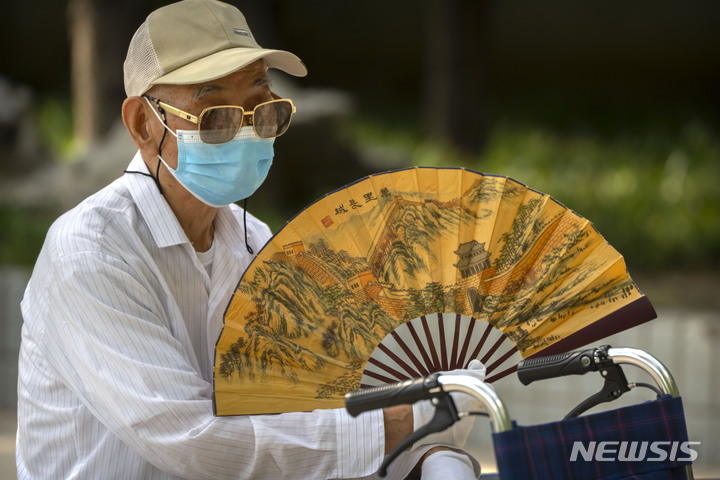 [베이징=AP/뉴시스]지난 7월8일 베이징의 한 공원에서 마스크를 쓴 노인 한 명이 부채질을 하고 있다. 고령자들에게 백신을 접종받도록 한다는 중국 당국의 캠페인이 강력한 '제로 코로나' 규제 종식으로 이어질 수 있다는 희망을 부르고 있다. 고령자들의 백신 접종률 저조는 중국이 엄격한 규제를 계속하게 만들어온 최대 장애물 중 하나로 꼽혀 왔다. 2022.11.30