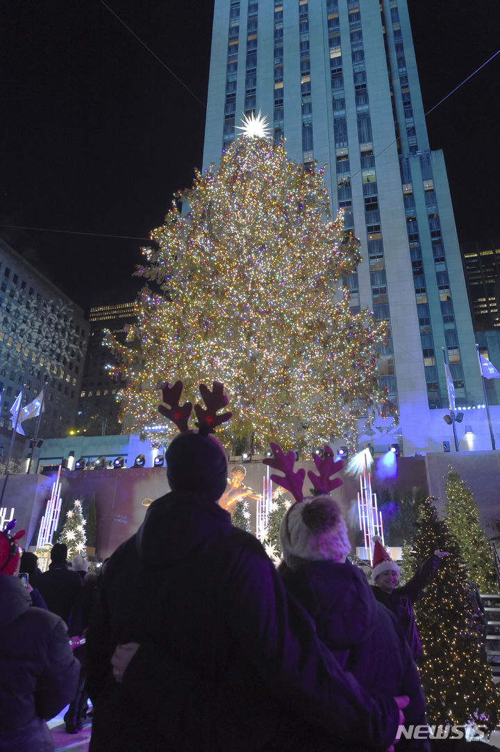 [뉴욕=AP/뉴시스] 지난 2022년 11월 30일(현지시간) 미국 뉴욕 록펠러 센터에서 열린 크리스마스 트리 점등식에 참석한 관람객들이 트리를 보고 있다. 2023.11.10.