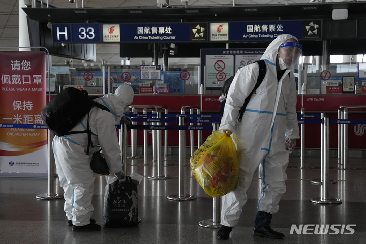 [베이징=AP/뉴시스]중국 베이징의 공항 터미널에서 13일 방호복을 입은 승객들이 짐을 들고 있다. 중국이 베이징에서 코로나19 감염이 급증함에 따라 주요 경제회의인 중앙경제공작회의를 미루고 있다고 일본 지지(時事)통신과 야후 뉴스가 블룸버그통신과 로이터 통신 보도를 인용해 13일 전했다. 2022.12.13