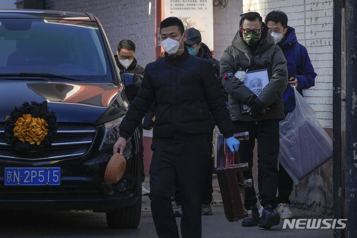 [베이징=AP/뉴시스] 19일 중국 베이징의 한 발열 전담병원에서 사람들이 영정사진과 장례용품 등을 들고 운구차량 옆을 지나고 있다. 2022.12.20