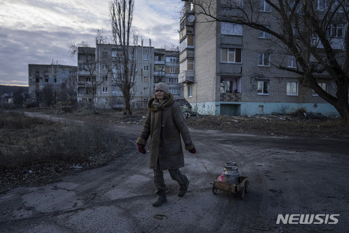 [하르키우=AP/뉴시스] 러시아군의 공격으로 물과 전기 공급이 끊긴 우크라이나 하르키우주 한 지역에서 한 여성이 카트에 물이 든 양동이를 싣고 가고 있다. 2022.12.30. 