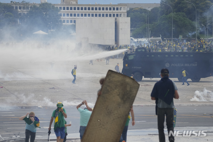 [브라질리아=AP/뉴시스] 8일(현지시간) 브라질 수도 브라질리아에서 자이르 보우소나루 전 대통령을 지지하는 시위대가 루이스 이나시우 룰라 다시우바 대통령의 집무실이 있는 플라날토궁을 습격해 최루 가스를 살포하는 경찰 차량에 맞서고 있다. 룰라 대통령은 시위대를 '광신도, 파시스트'라고 부르며 "모든 법령을 동원해 죄를 물을 것"이라고 밝혔다. 2023.01.09.