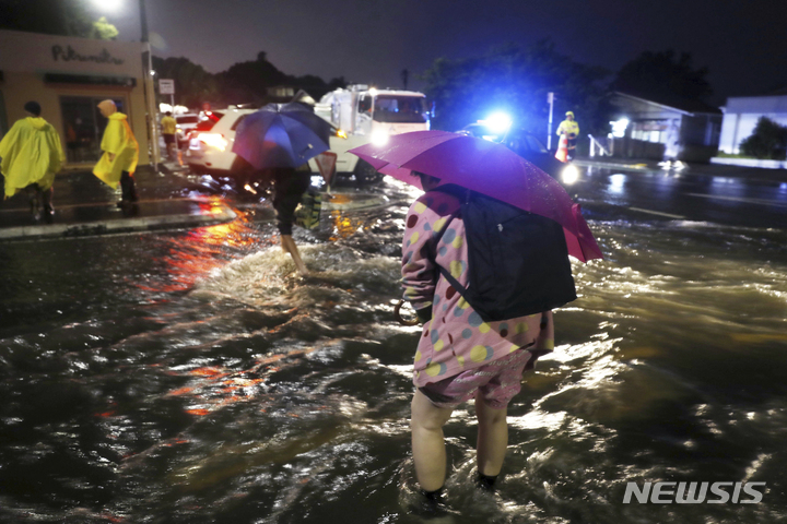 [오클랜드=AP/뉴시스]27일(현지시간) 오클랜드의 물에 잠긴 거리를 사람들이 건너고 있다. 기록적인 폭우가 뉴질랜드 최대 도시를 강타해 광범위한 혼란을 야기했다. 2023.01.28.