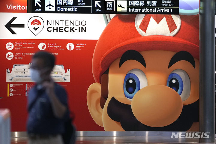 [도쿄=AP/뉴시스]지난 6월 10일 일본 도쿄 인근 나리타 공항에서 한 여행객이 닌텐도 광고판 앞을 지나가고 있다. 2023.08.10.
