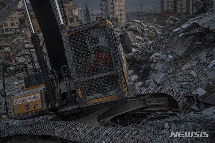 [안타키아=AP/뉴시스] 12일(현지시간) 튀르키예 안타키아에서 한 굴착기 운전자가 건물 잔해에서 지진 피해자의 시신을 수습하기 위해 구조대를 기다리고 있다. 2023.02.13.