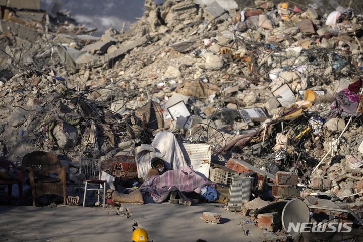 [카라만마라슈=AP/뉴시스] 13일(현지시간) 튀르키예 카라만마라슈에서 한 주민이 지진으로 파괴된 건물 잔해 주변에 누워 잠자고 있다. 강진 발생 8일째에 접어들면서 튀르키예와 시리아의 사망자 숫자는 3만 6000명을 넘어섰다. 2023.02.14.