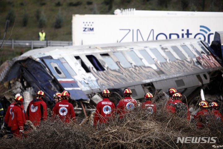 [라리사=AP/뉴시스] 1일(현지시간) 그리스 아테네 북쪽에서 376km 떨어진 템페 인근에서 화물열차와 여객열차의 충돌로 구조대원들이 파손된 열차 근처에 서 있다. 2023.03.02.