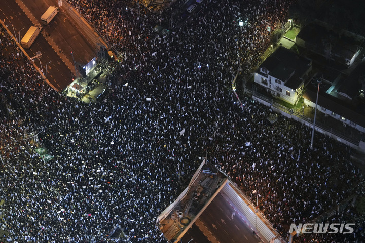 [텔아비브(이스라엘)=AP/뉴시스]베냐민 네타냐후 총리 정부의 법 개정 추진에 반대하는 이스라엘 국민 수만명이 지난 4일 텔아비브에서 대규모 항의 시위를 벌이고 있다. 이스라엘 의회가 6일 두 달 넘게 이어지는 국민들의 거센 항의에도 불구, 베냐민 네타냐후 이스라엘 총리가 지금은 숨진 사촌으로부터 받은 27만 달러(약 3억5140만원)의 기부금을 부패 혐의를 둘러싼 총리 재판의 법정 비용으로 쓸 수 있도록 하는 법안을 찬성 53대 반대 49로 통과시켰다. 2023.3.6