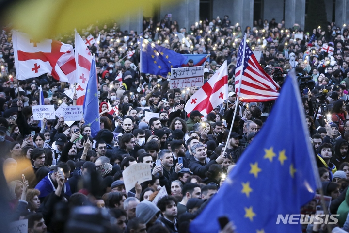[트빌리시=AP/뉴시스] 8일(현지시간) 조지아 트빌리시 의회 건물 밖에서 반정부 시위대가 미국, 우크라이나, 조지아 국기와 유럽연합 깃발을 흔들고 있다. 조지아 의회가 언론의 자유와 시민사회 활동을 침해할 수 있는 '외국 대리인(foreign agents)법' 추진을 강행해 이틀째 격렬한 시위가 이어지고 있으며 경찰은 최루탄과 물대포를 쏘면서 시위대를 제지하고 있다. 2023.03.09.
