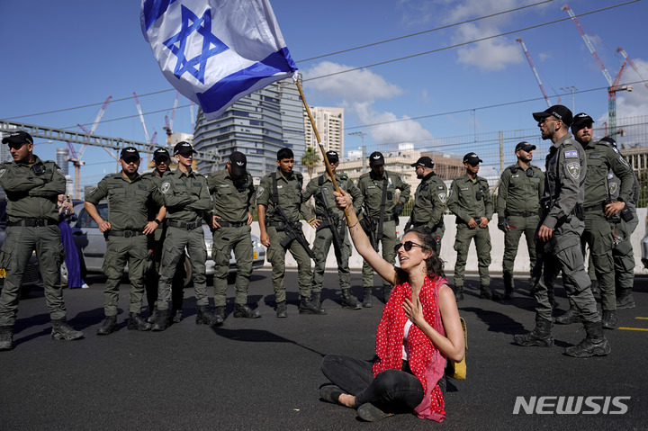 [텔아비브=AP/뉴시스] 9일(현지시간) 이스라엘 텔아비브에서 베냐민 네타냐후 총리 정부의 사법제도 개혁 추진에 반대하는 시위 참가자가 경찰관들 앞에서 국기를 흔들고 있다. 두 달 넘게 사법 개혁 반대 시위를 벌여온 시위대는 9일을 '독재에 대한 저항의 날'로 선포하고 새로운 시위를 시작했다. 2023.03.10.