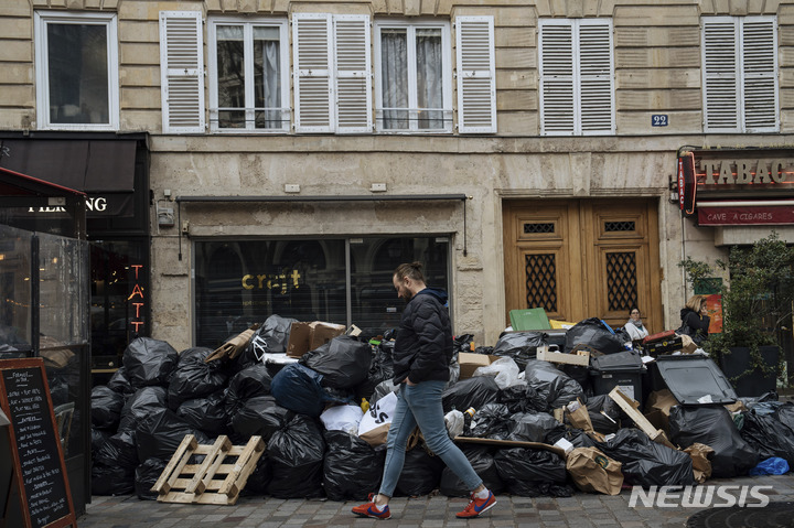 [파리=AP/뉴시스] 13일(현지시간) 프랑스 파리에서 시민이 수거되지 않은 쓰레기 더미 앞을 지나고 있다. 정년을 62세에서 64세로 올리는 것을 골자로 한 연금개혁에 반대하는 시위와 파업이 이어지면서 거리 곳곳에는 수거하지 않은 쓰레기가 늘어가고 있다. 정부가 추진하는 연금개혁법안은 노조의 거센 반발에도 지난 11일 상원을 통과했다. 2023.03.14.
