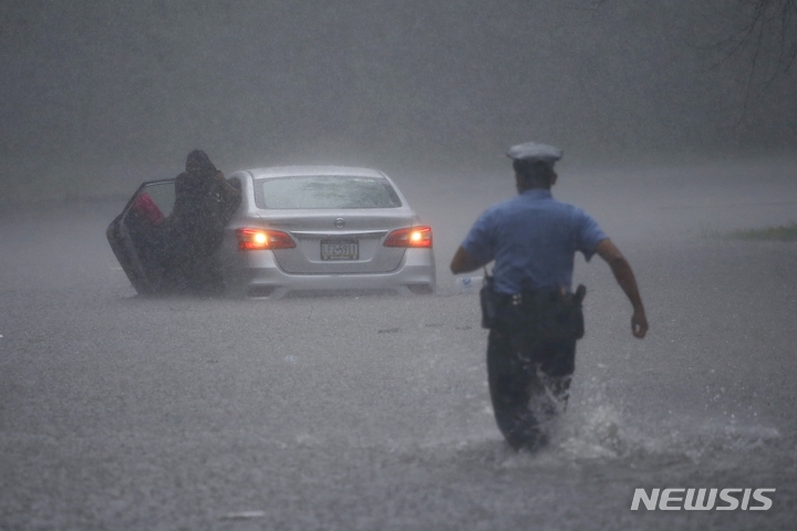 [필라델피아=AP/뉴시스] 기후변화로 폭우와 홍수에 시달리는 미 동부 필라델피아 시에서 경찰관이 물에 빠진 차량을 향해 달려가고 있다. (2023년 3월 13일자 '네이처 워터'지 사진) 2023.06.01 