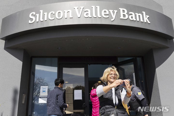 [산타클라라=AP/뉴시스]13일(현지시간) 미국 캘리포니아주 산타클라라 실리콘밸리은행(SVB) 본점 앞에서 돈을 찾기 위해 대기하다 입장하게 된 여성이 셀카를 찍고 있다. 이날 예금주들은 은행 밖에서 줄을 서서 대기했다. 2023.03.14