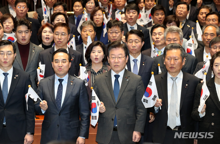 [서울=뉴시스] 이영환 기자 = 이재명 더불어민주당 대표와 박홍근 원내대표 및 의원들이 16일 오후 서울 여의도 국회 예결위회의장에서 열린 의원총회에서 태극기를 들고 발언하고 있다. 2023.03.16. 20hwan@newsis.com