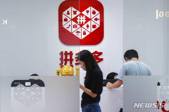 [상하이=AP/뉴시스]지난 2018년 7월25일 상하이에서 한 여성이 로고가 붙어 있는 핀둬둬 본사의 접수대 앞을 지나가고 있다. 구글이 21일 다른 소스의 앱 버전에서 악성코드가 발견됨에 따라 앱스토어에서 중국 쇼핑 앱 핀둬둬를 정지시켰다. 2023.3.21