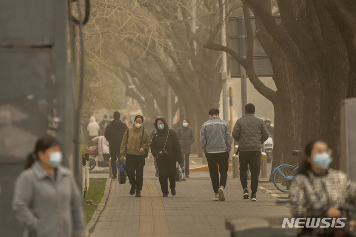 [베이징=AP/뉴시스] 22일 중국 베이징의 중심가에서 마스크를 쓴 시민들이 거리를 걷고 있다. 이날 아침 베이징은 황사와 모래폭풍으로 대기질 지수가 치솟았다. 2023.03.22.
