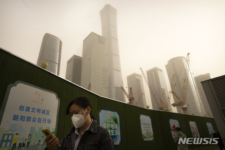 [베이징=AP/뉴시스] 22일 중국 베이징에서 마스크를 쓴 시민이 거리를 걷고 있다. 이날 아침 베이징은 황사와 모래폭풍으로 대기질 지수가 치솟았다. 2023.03.22.