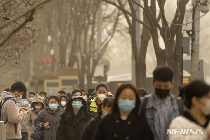 [베이징=AP/뉴시스] 22일 중국 베이징의 중심가에서 마스크를 쓴 시민들이 거리를 걷고 있다. 환경부는 오는 23일부터 황사 유입이 예상됨에 따라 인천, 경기 지역에 22일 오후 5시 기준으로 황사 위기경보 관심 단계를 발령했다. 2023.03.22.