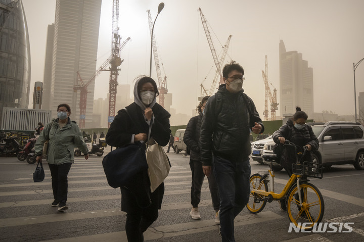 [베이징=AP/뉴시스] 22일 중국 베이징의 중심가에서 마스크를 쓴 시민들이 교차로를 건너고 있다. 이날 아침 베이징은 황사와 모래폭풍으로 대기질 지수가 치솟았다. 2023.03.22.