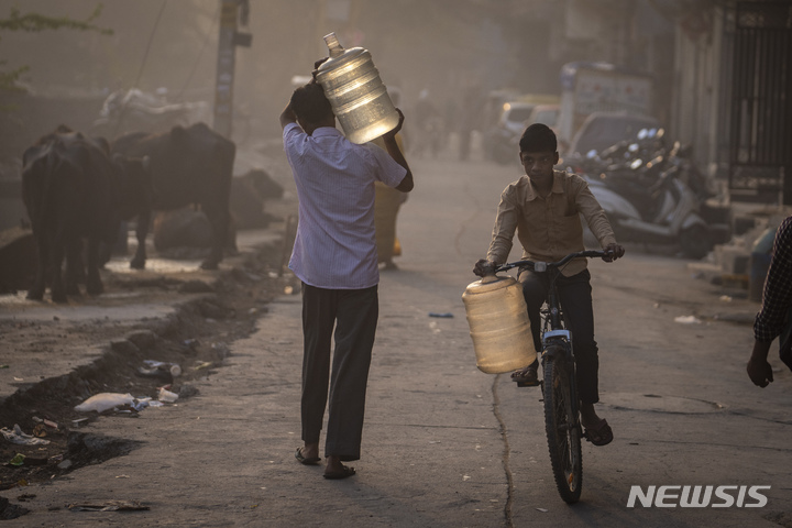 [뉴델리(인도)=AP/뉴시스]세계 물의 날인 22일 인도 뉴델리에서 한 소년이 물을 받기 위해 자전거에 물통을 달고 물공급차로 가는 옆을 이미 물을 받은 한 남성이 물통을 어깨에 메고 걸어가고 있다. 22일 '세계 물의 날'을 맞아 45년 만에 처음 열리는 유엔의 물 관련 주요 회의를 하루 앞두고 21일에 발표된 새 보고서에 따르면 세계 인구의 26%가 안전한 식수를 이용할 수 없고, 46%는 기본적 위생시설 접근이 불가능한 것으로 드러났다. 2023.3.22