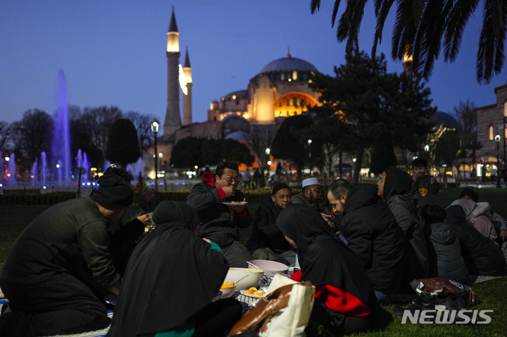 [이스탄불=AP/뉴시스] 23일(현지시간) 튀르키예 이스탄불에 있는 아야 소피아 사원 앞에서 라마단 첫날 금식을 마친 무슬림들이 이프타르를 함께 하고 있다. 전 세계 이슬람교도들은 다음 초승달이 뜰 때까지 이어지는 라마단 기간 새벽부터 해 질 녘까지 금식하고 일몰 후에는 가족, 친지, 이웃과 함께하는 만찬 '이프타르'를 즐긴다. 2023.03.24.