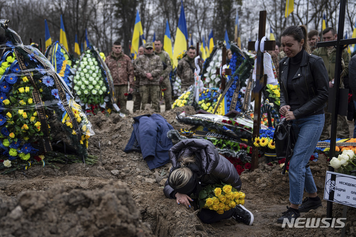 [키이우=AP/뉴시스] 25일(현지시간) 우크라이나 키이우에서 러시아군과 전투 중 숨진 우크라이나 군인 안드리이 네쇼도우스키의 장례식이 열려 고인의 부인 나탈리아가 무덤에 주저앉아 흐느끼고 있다. 2023.03.26.