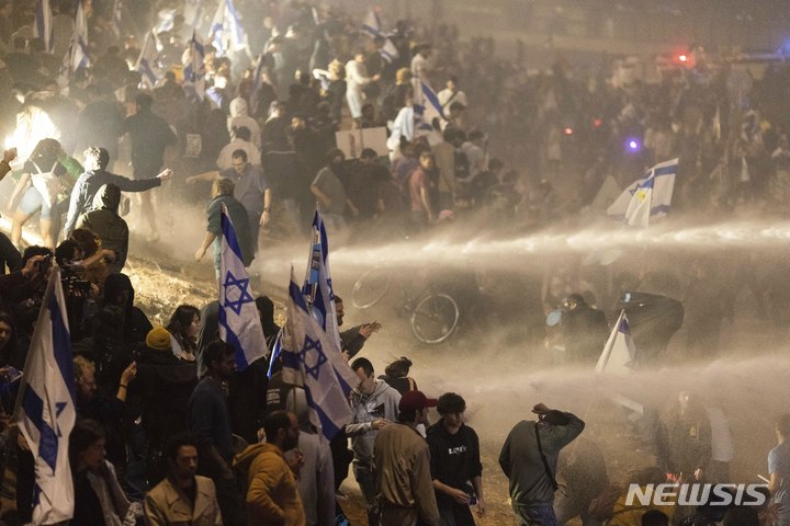 [텔아비브=AP/뉴시스]26일(현지시간) 이스라엘 텔아비브에서 사법 개혁 반대 시위대가 고속도로를 막고 시위를 벌이자 경찰이 물대포를 쏘고 있다. 2023.03.27