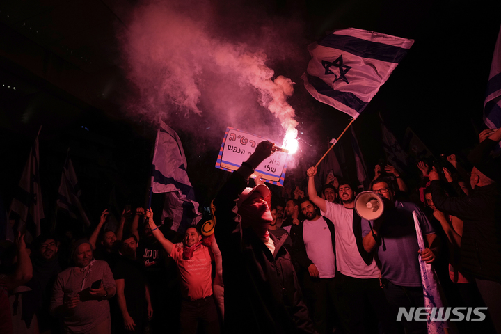 [텔아비브=AP/뉴시스] 26일(현지시간) 이스라엘 텔아비브에서 사법 개혁 반대 시위대가 베냐민 네타냐후 총리의 국방장관 해임 이후 고속도로를 막고 시위를 벌이고 있다. 2023.03.27.