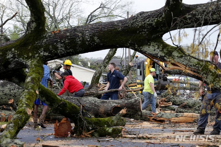 [셔우드=AP/뉴시스]3월31일(현지시간) 미국 아칸소주 셔우드 지역에서 폭풍이 몰아친 후 경찰과 소방관들이 자원봉사자들과 함께 쓰러진 나무를 치우고 있다. 2023.04.01.