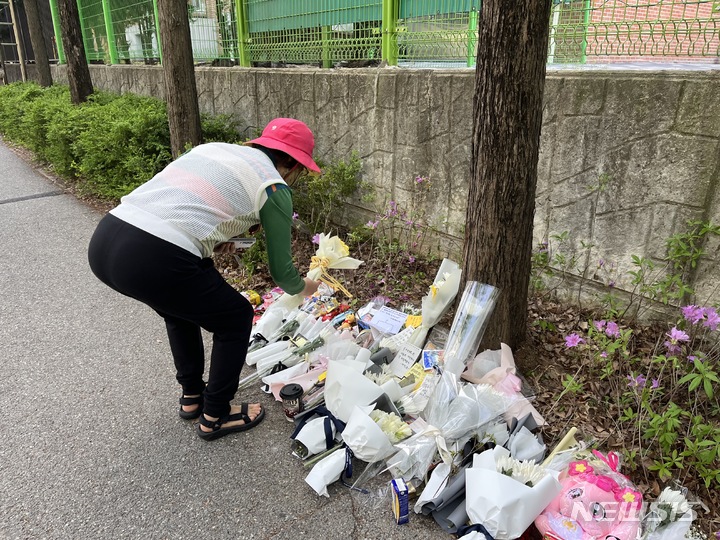 [대전=뉴시스] 김도현 기자 = 10일 오전 대전 서구 둔산동의 한 초등학교 인근에서 한 시민이 음주운전 사고로 사망한 9살 초등학생을 추모하기 위해 헌화하고 있다.2023.04.10. photo@newsis.com