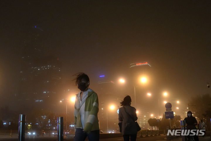[베이징=AP/뉴시스] 10일 중국 베이징에서 마스크를 쓴 주민들이 모래폭풍이 불어오는 거리를 걷고 있다. 황사와 모래폭풍이 이날 밤 베이징을 덮쳐 대기지수(AQI)가 치솟았다. 2023.04.11.