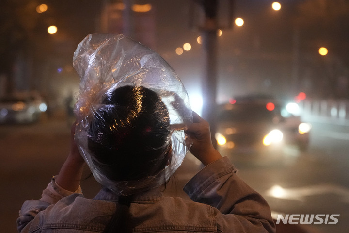 [베이징=AP/뉴시스] 10일 중국 베이징에서 한 주민이 비닐봉지를 뒤집어쓰고 모래폭풍을 피하고 있다. 황사와 모래폭풍이 이날 밤 베이징을 덮쳐 대기지수(AQI)가 치솟았다. 2023.04.11.