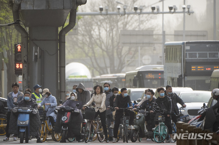 [베이징=AP/뉴시스] 11일 중국 베이징에서 이륜차를 탄 출근길 시민들이 마스크를 쓴 채 황사에 뒤덮인 시내 교차로에서 대기하고 있다. 전날 밤부터 베이징을 덮친 황사와 모래폭풍으로 강풍 경보와 황사 경보가 동시에 발령됐다. 2023.04.11.