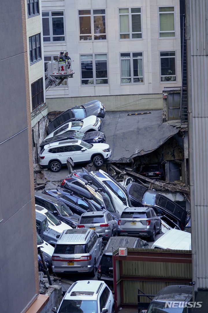 [뉴욕=AP/뉴시스] 4월 18일 뉴욕 금융가 주차빌딩 붕괴 현장에서 소방대 출동장면을 옆 건물의 한 남성이 창문을 통해 지켜보고 있다.