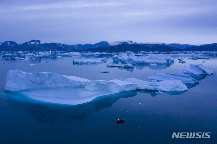 [쿨루수크(그린란드)=AP/뉴시스] 2019년 8월15일 밤 그린란드 동부 쿨루수크 마을 근처 큰 빙산 옆을 배 한 척이 항해하고 있다. 그린란드와 남극에서 1년 간 녹아 없어지는 빙상의 양이 30년 전에 비해 3배 이상에 달하는 것으로 새로운 포괄적인 국제 연구 결과 밝혀졌다. 이 같은 변화로 대서양자오선전복해류의 흐름이 멈추면 지구에 기후 대재앙이 닥칠 것이라는 경고가 나왔다. 2023.07.26.